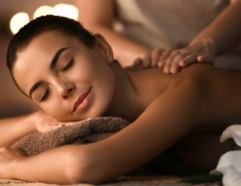 Beautiful young woman receiving massage in spa salon